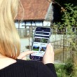 Eine Frau schaut auf ein Handy, im Hintergrund eine Wassermühle
