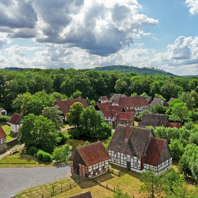 Luftaufnahme des Paderborner Dorfes im Museum, einem kleinen Dorf mit Fachwerkhäusern, umgeben von Wiesen. (vergrößerte Bildansicht wird geöffnet)