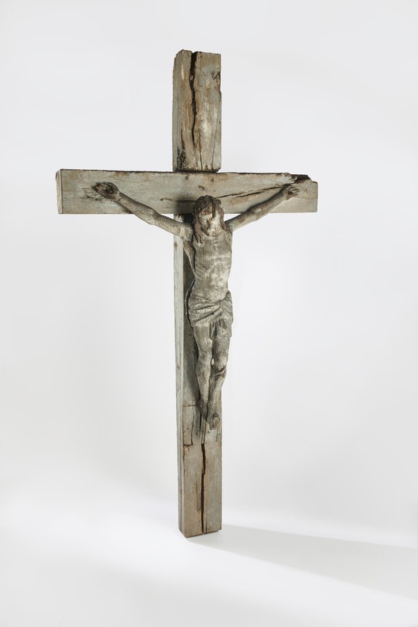 Ein hölzernes Kreuz mit Christusfigur vor weißem Hintergrund