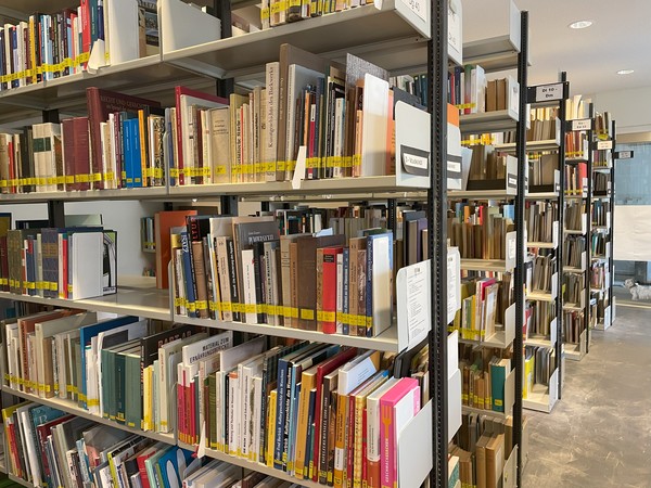 Hintereinander stehen vier deckenhohe Regale voller Bücher.
