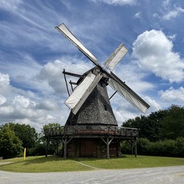 Eine Mühle mit bespannten Flügeln auf einer Wiese