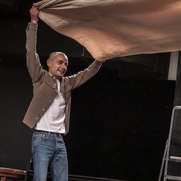 Szene aus dem Theaterstück All das Schöne. Man hebt eine Tischdecke hoch in die Luft.