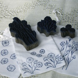 Weißer Stoff, mit blauen Motiven bedruckt, daneben liegen drei schwarze Stempel
